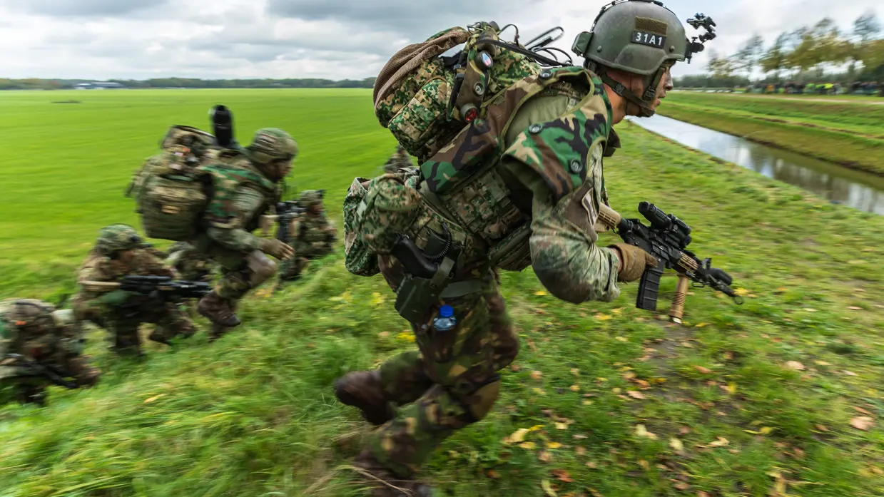 Militairen oefenen in een weiland.