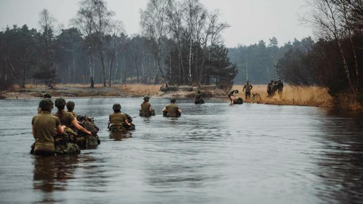 Militairen waden door het water.