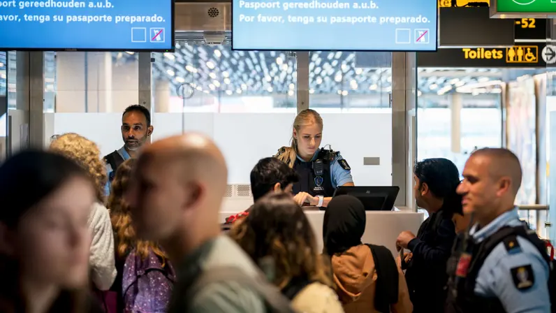 Twee marechaussees controleren documenten op Schiphol.