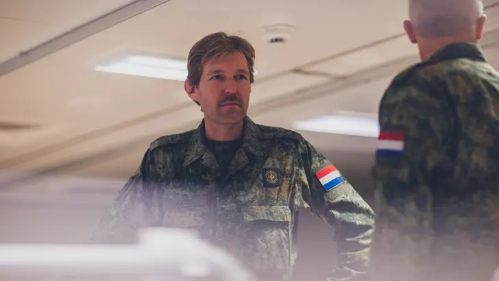 Militair aan boord, achter ziekenhuisbed.