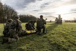 Militairen op de rug gezien, met daarachter een helikopter.