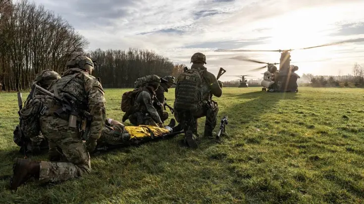 militair op de rug gezien, daarachter een helikopter.