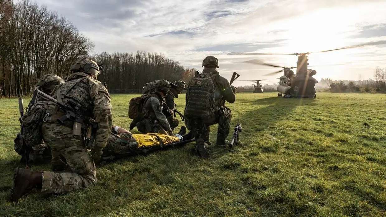militair op de rug gezien, daarachter een helikopter.
