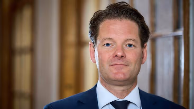Portret vanaf de schouders van secretaris-generaal Maarten Schurink. De SG draagt een blauw pak en kijkt recht in de camera.