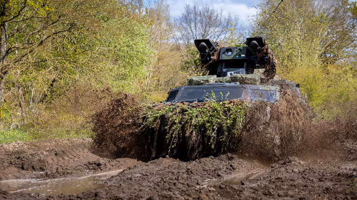 Het Stinger Weapon Platform Fennek rijdt dwars door de modder.