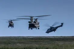 Drie helikopters vliegen laag boven de grond.