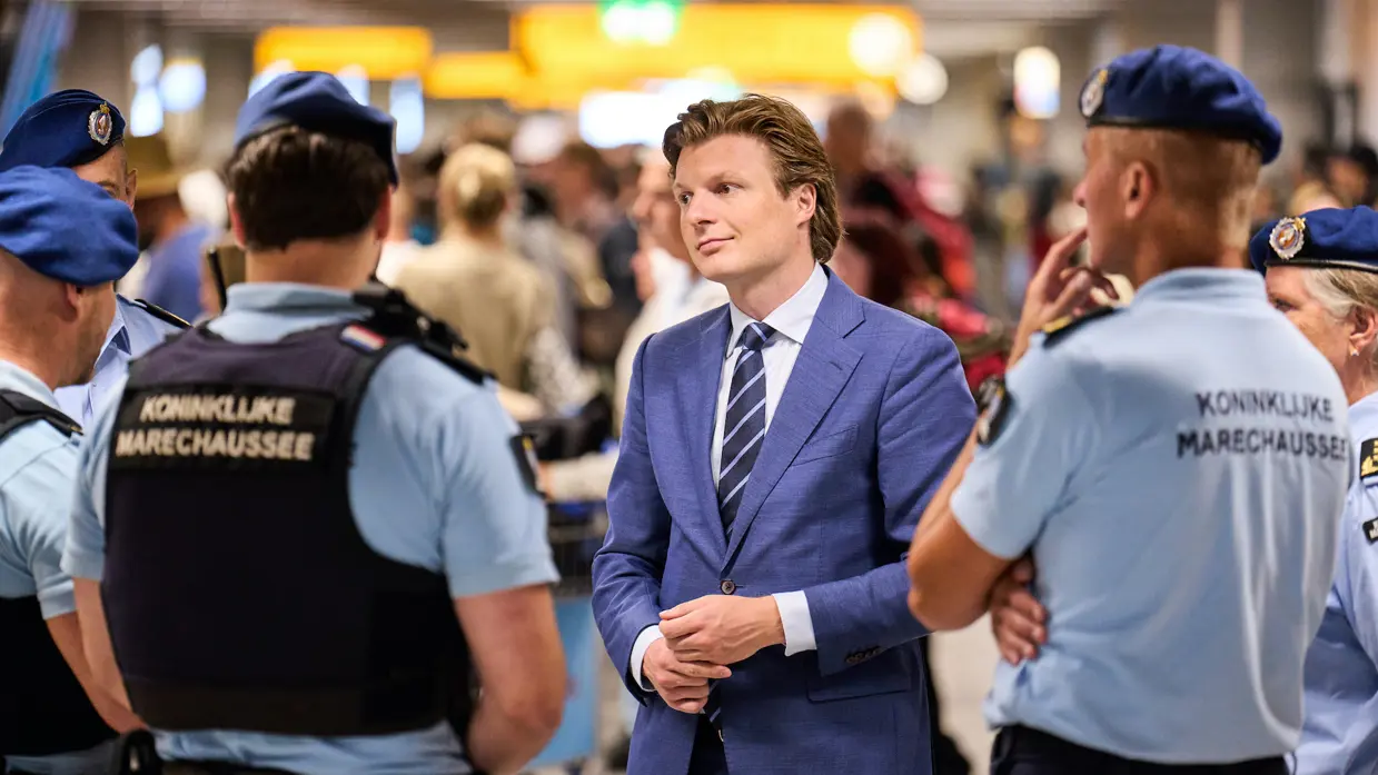  Staatssecretaris Tuinman praat met militairen in ME-tenue. Minister Brekelmans praat met een groepje marechaussees op Schiphol.