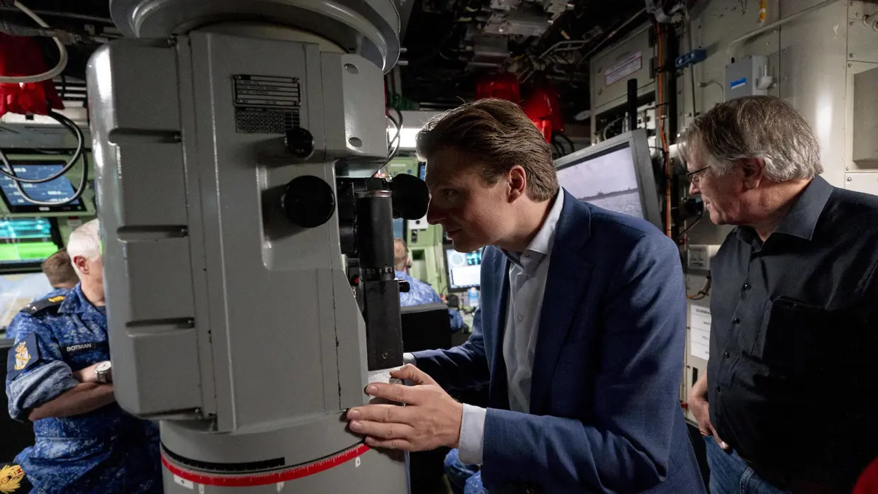 Minister Brekelmans kijkt door een periscoop.&nbsp;