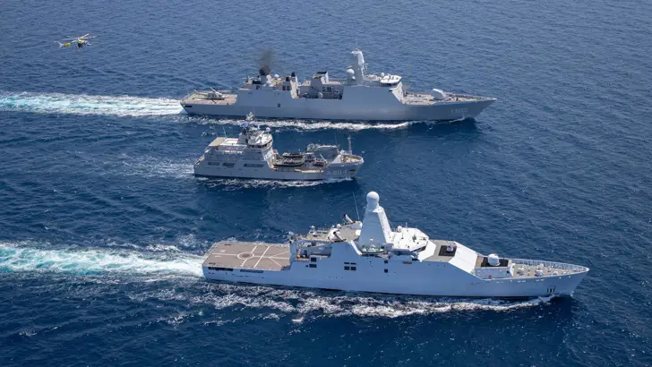 2 marineschepen op zee met in het midden een kustwachtvaartuig.