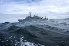 Marineschip vaart door woeste golven.