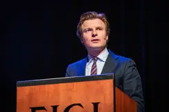 Minister Brekelmans geeft toespraak vanachter katheder.