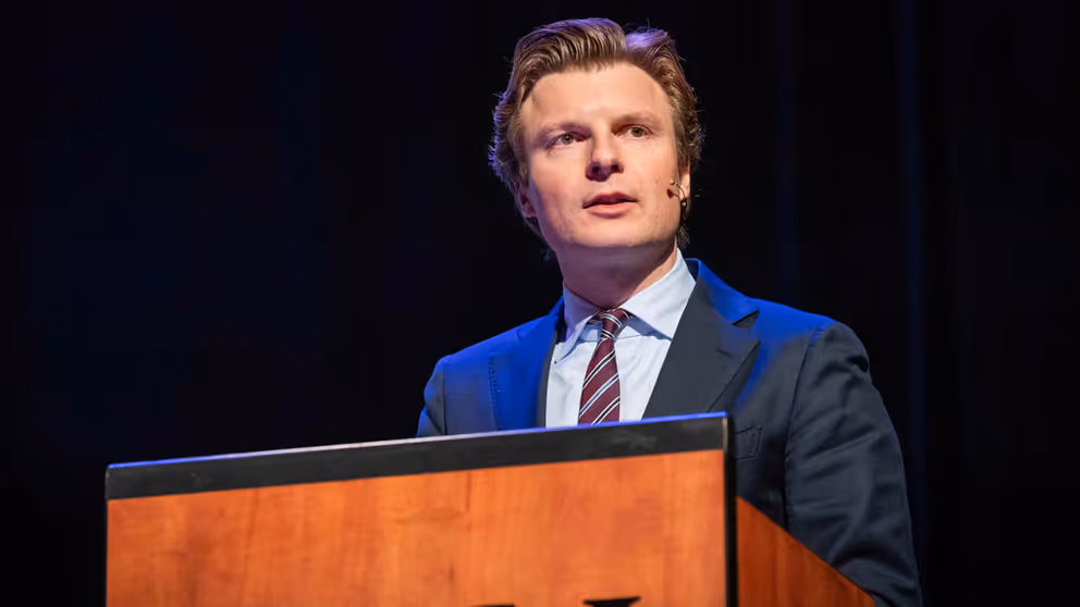 Minister Brekelmans geeft toespraak vanachter katheder.