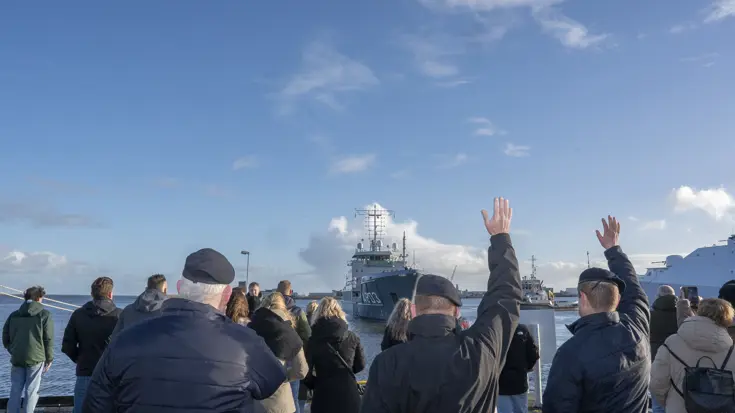 Mensen zwaaien een marineschip uit.