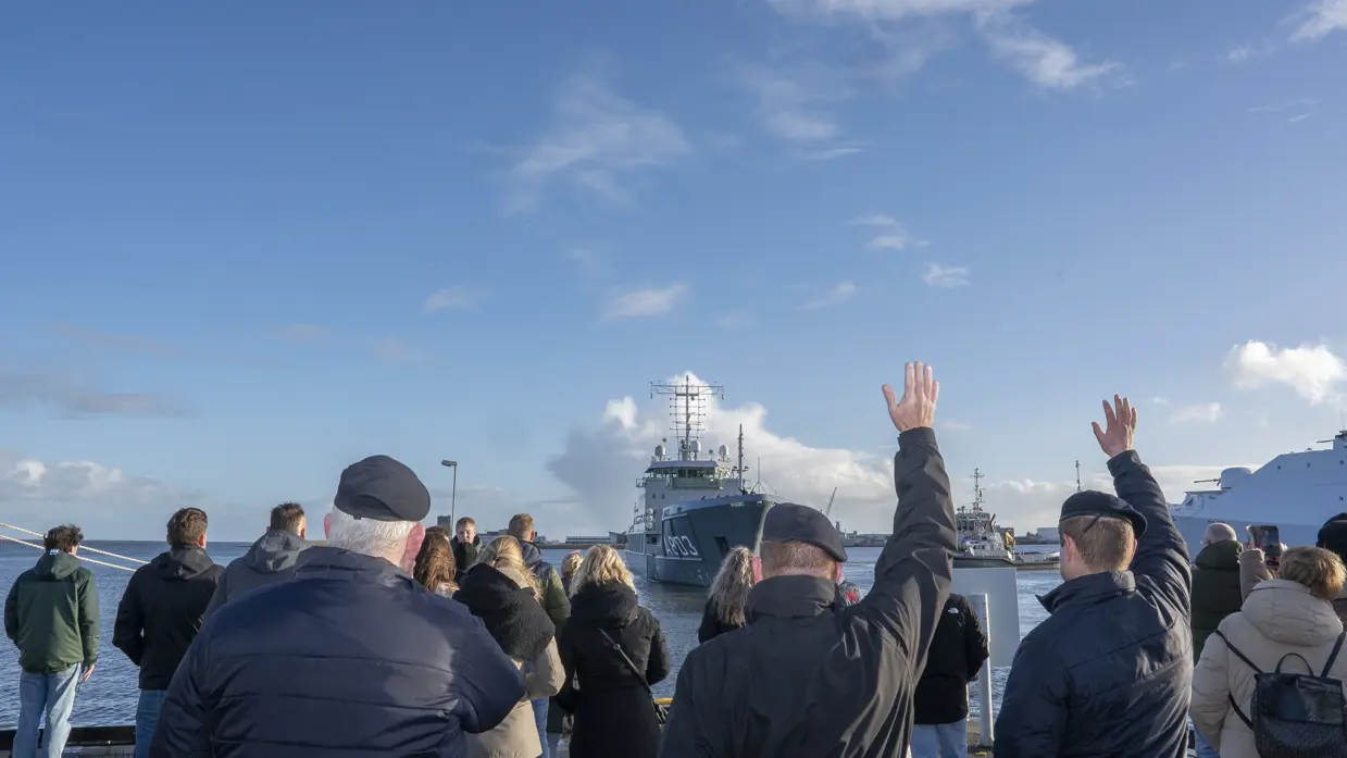 Mensen zwaaien een marineschip uit.
