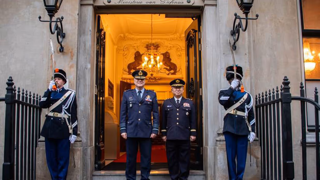Commandant der Strijdkrachten generaal Onno Eichelsheim en generaal Yoshihide Yoshida staan voor de deur van het ministerie. Ze worden geflankeerd door een erewacht.