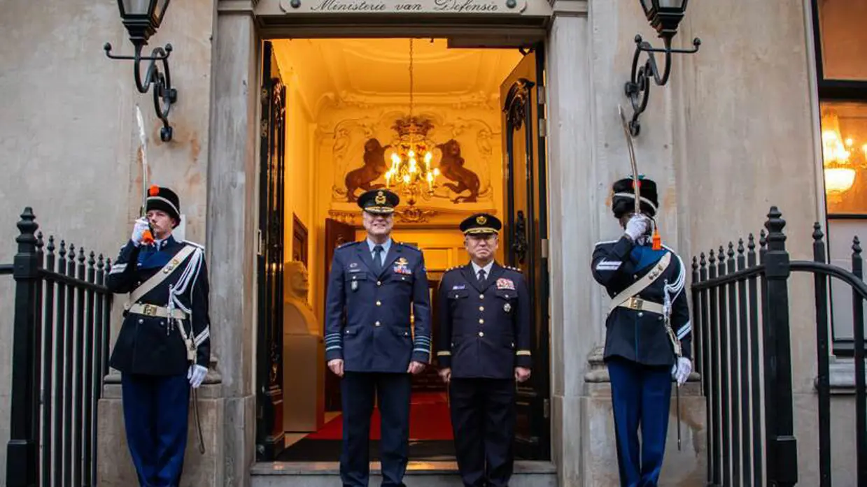 Commandant der Strijdkrachten generaal Onno Eichelsheim en generaal Yoshihide Yoshida staan voor de deur van het ministerie. Ze worden geflankeerd door een erewacht.