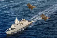 Zr.Ms. Tromp vaart op zee terwijl 2 gevechtsvliegtuigen er overheen vliegen.