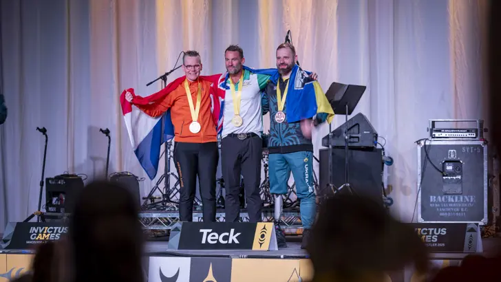 3 sporters op het podium met hun medailles.