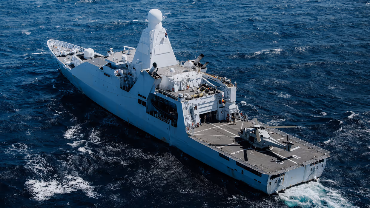 Marineschip met helikopter geland op dek.