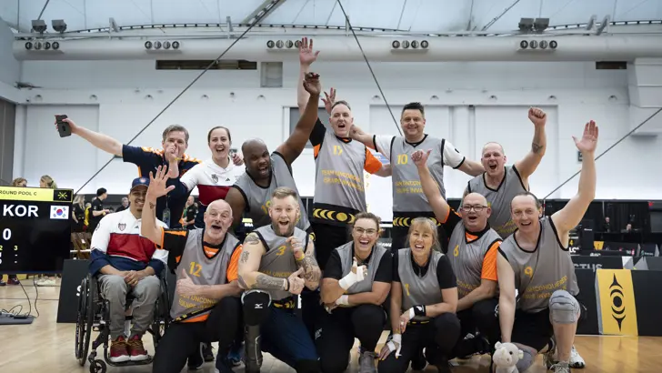 Een groep Nederlandse sporters poseren juichend voor de foto.