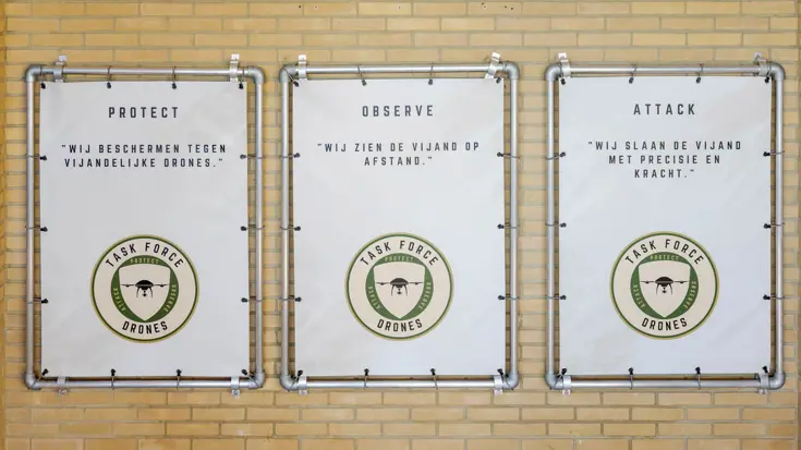 Een muur met daarop 3 afbeeldingen van de taakgroep drones.