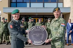 Luitenant-generaal Jan Swillens houdt met collega rond bord vast met de tekst: Task Force Drones. Opgestelde militairen op de achtergrond.