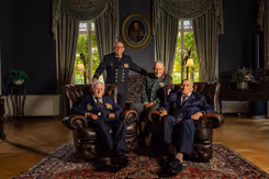 4 veteranen poseren, 2 van hen zitten in een stoel.