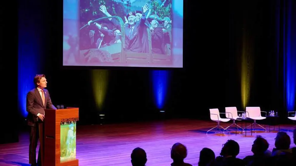 Minister Brekelmans spreekt vanaf podium volle zaal toe.