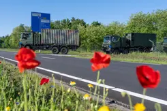 Trucks rijden een defensieterrein af.