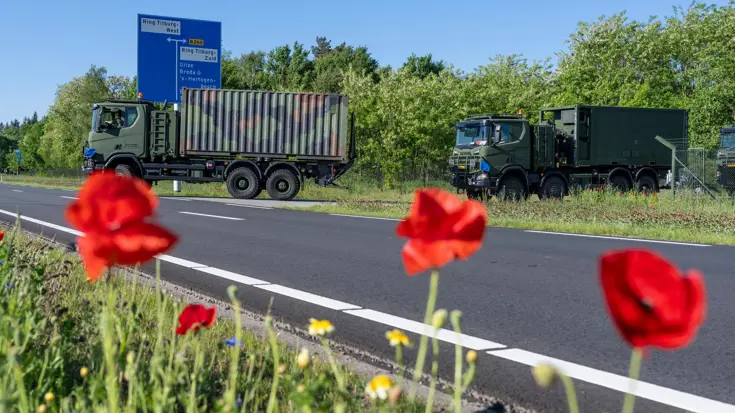Trucks rijden een defensieterrein af.