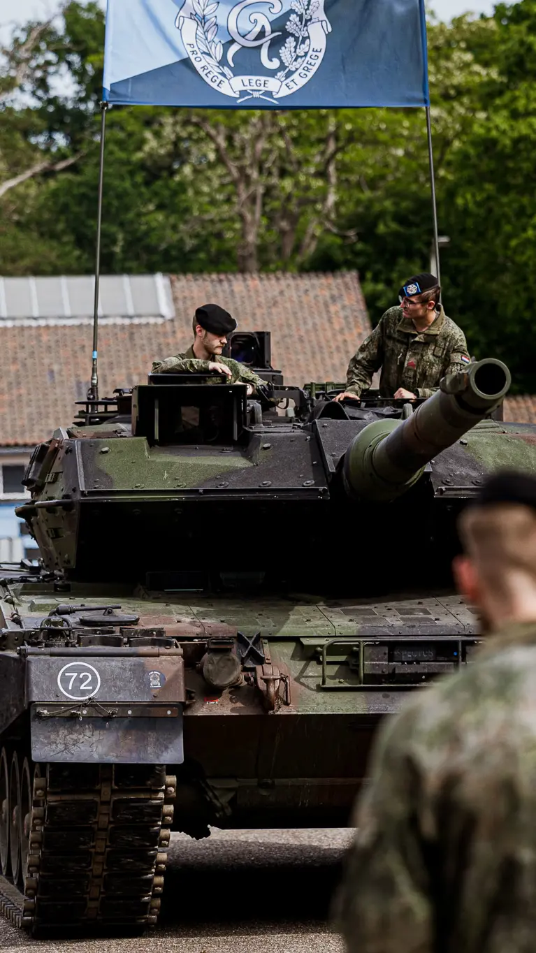 Militairen staan opgesteld voor een gevechtstank.  
