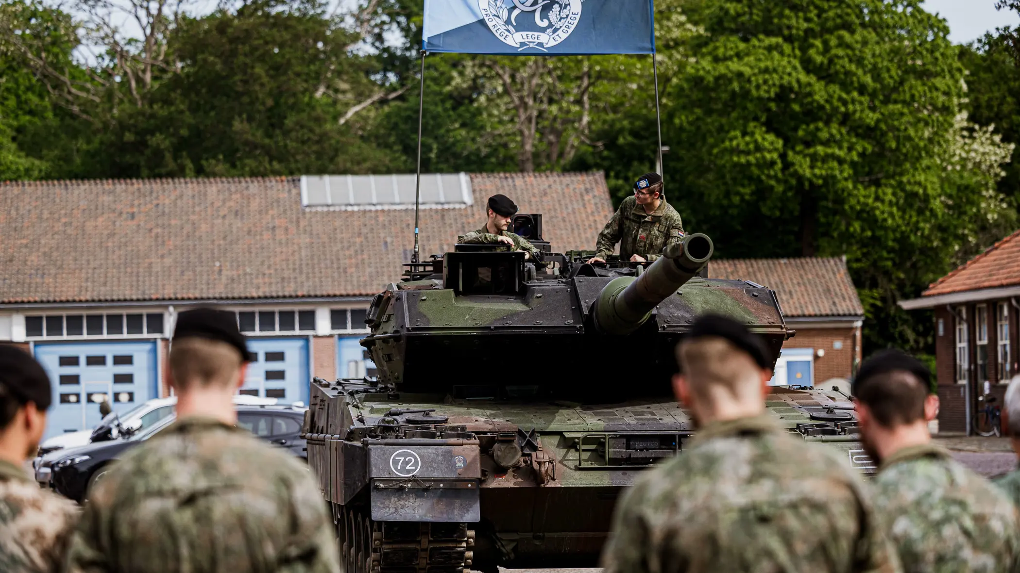 Militairen staan opgesteld voor een gevechtstank.  