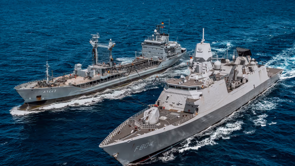 2 marineschepen naast elkaar op open water.