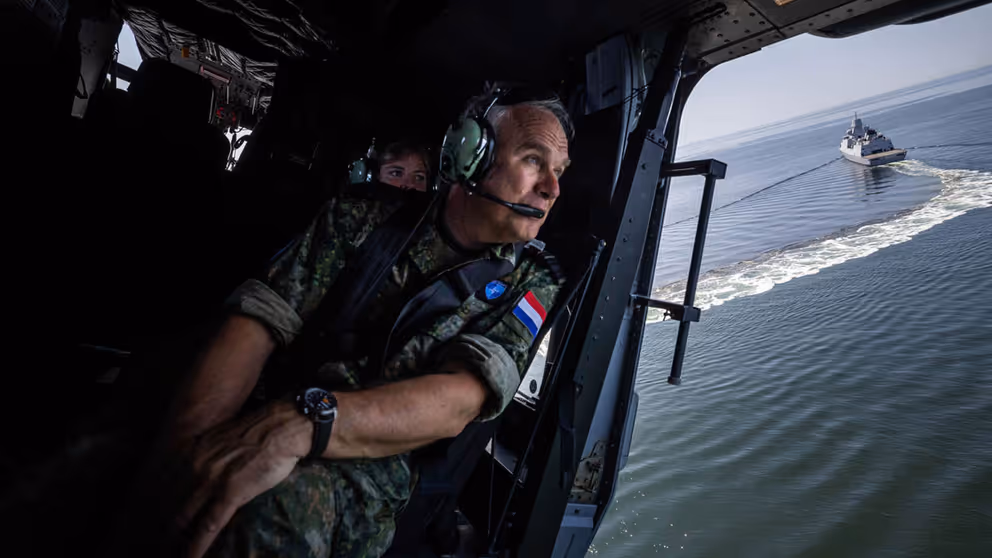 De commandant der Strijdkrachten in een helikopter boven zee. 