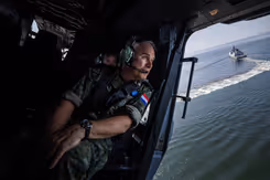 De commandant der Strijdkrachten in een helikopter boven zee. 