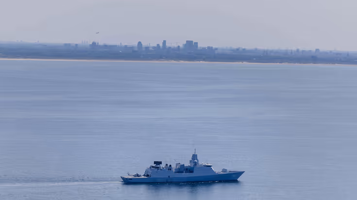 De marine vaart met enkele schepen voor de kust van Den Haag.