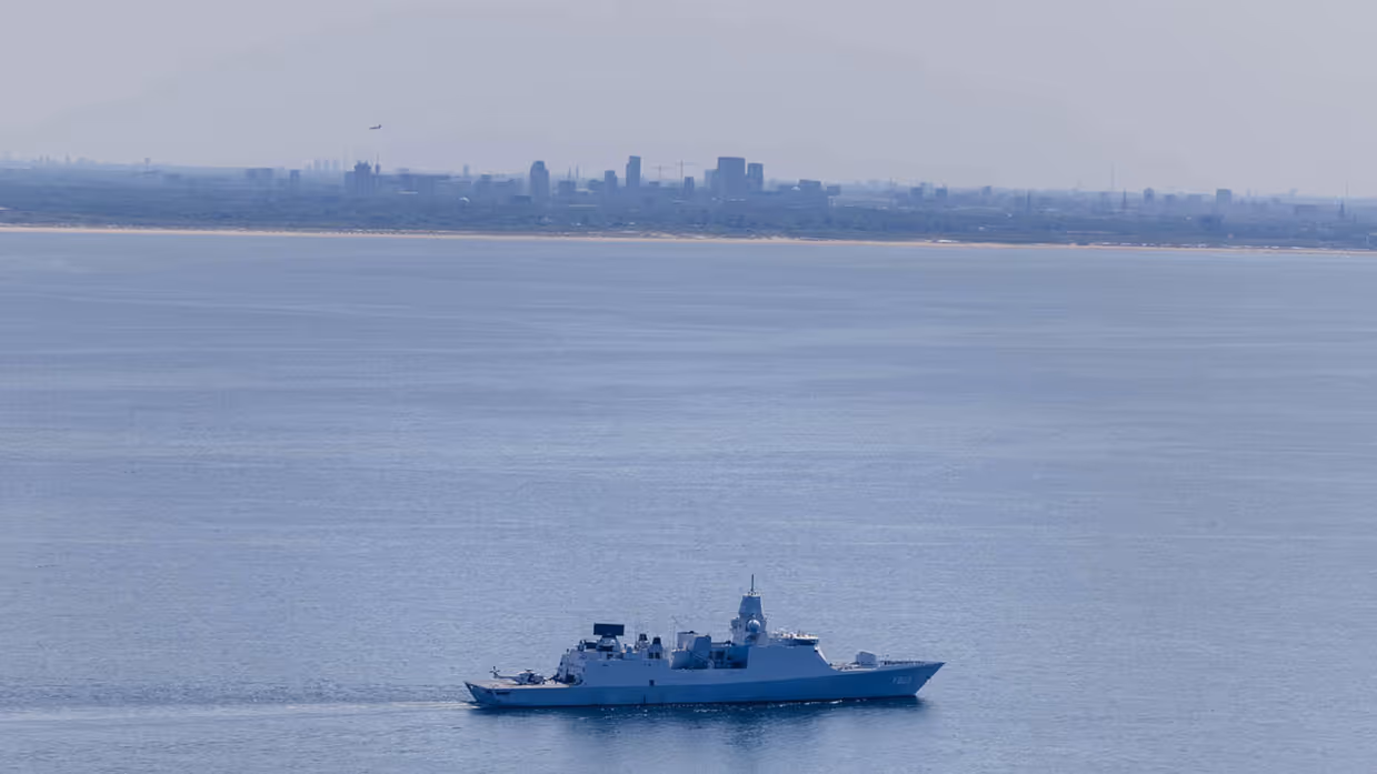 De marine vaart met enkele schepen voor de kust van Den Haag.