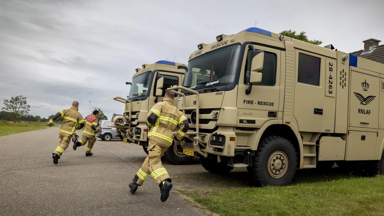 Militaire brandweermannen rennen over het platform naar hun wagens.