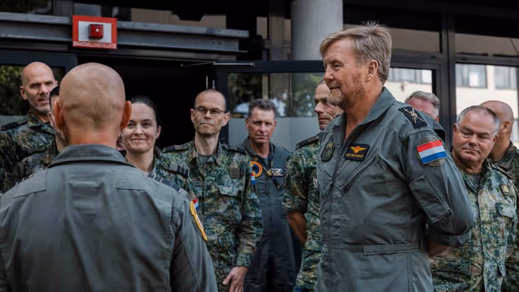 Koning Willem-Alexander in luchtmacht overall in gesprek met militairen.