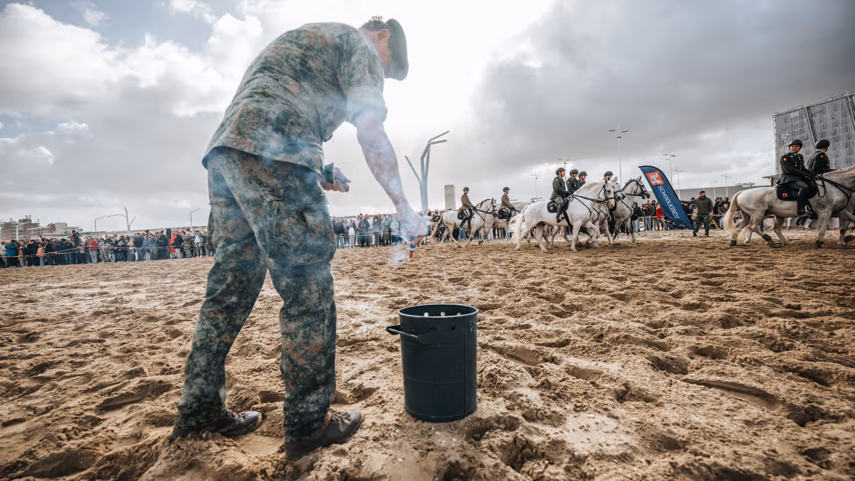 Militair op het strand steekt een rookpot aan.