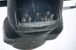 Parachutisten zitten klaar om uit het vliegtuig te springen. In het midden de koning. 