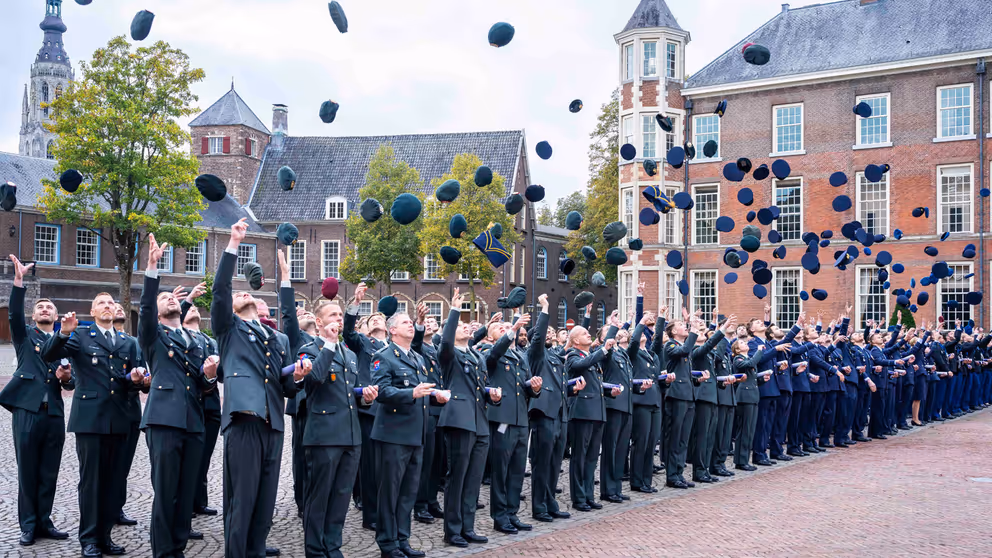 Officieren gooien hun pet in de lucht.