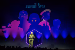 Generaal Eichelsheim staat op podium tegen blauwpaarse achtergrond.