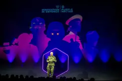 Generaal Eichelsheim staat op podium tegen blauwpaarse achtergrond.