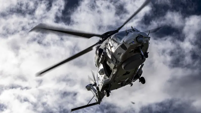 NH90 schuin van onderen tegen een blauwe lucht met bewolking.