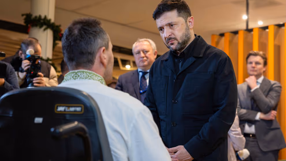 President Zelensky spreekt met een man in een rolstoel bij het Militair Revalidatiecentrum.