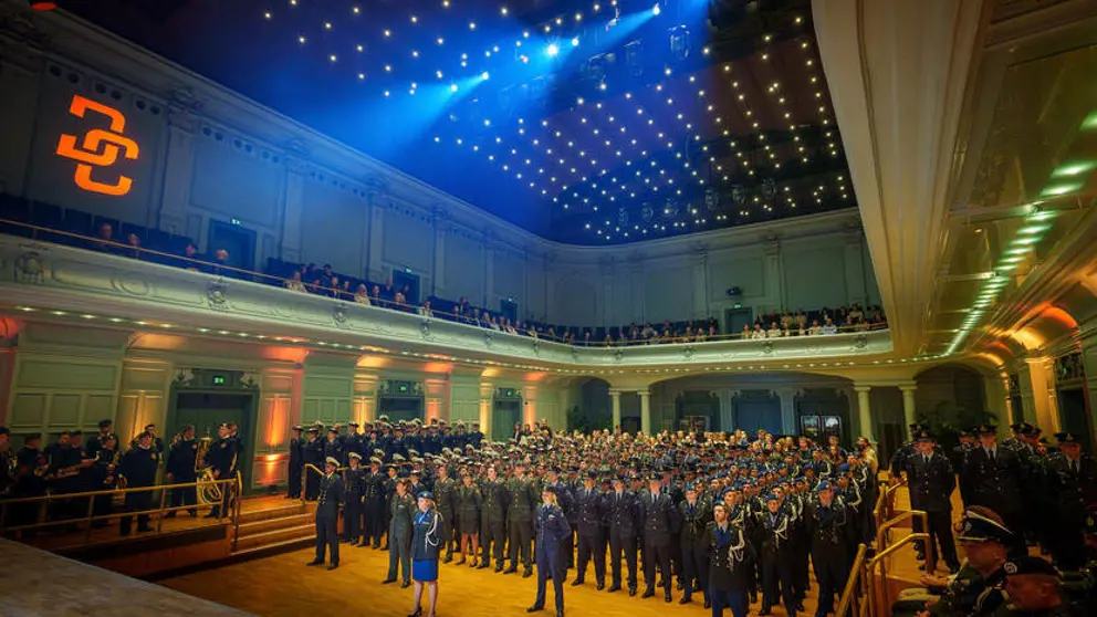 Zaal met honderden militairen die naar het podium staan te kijken.