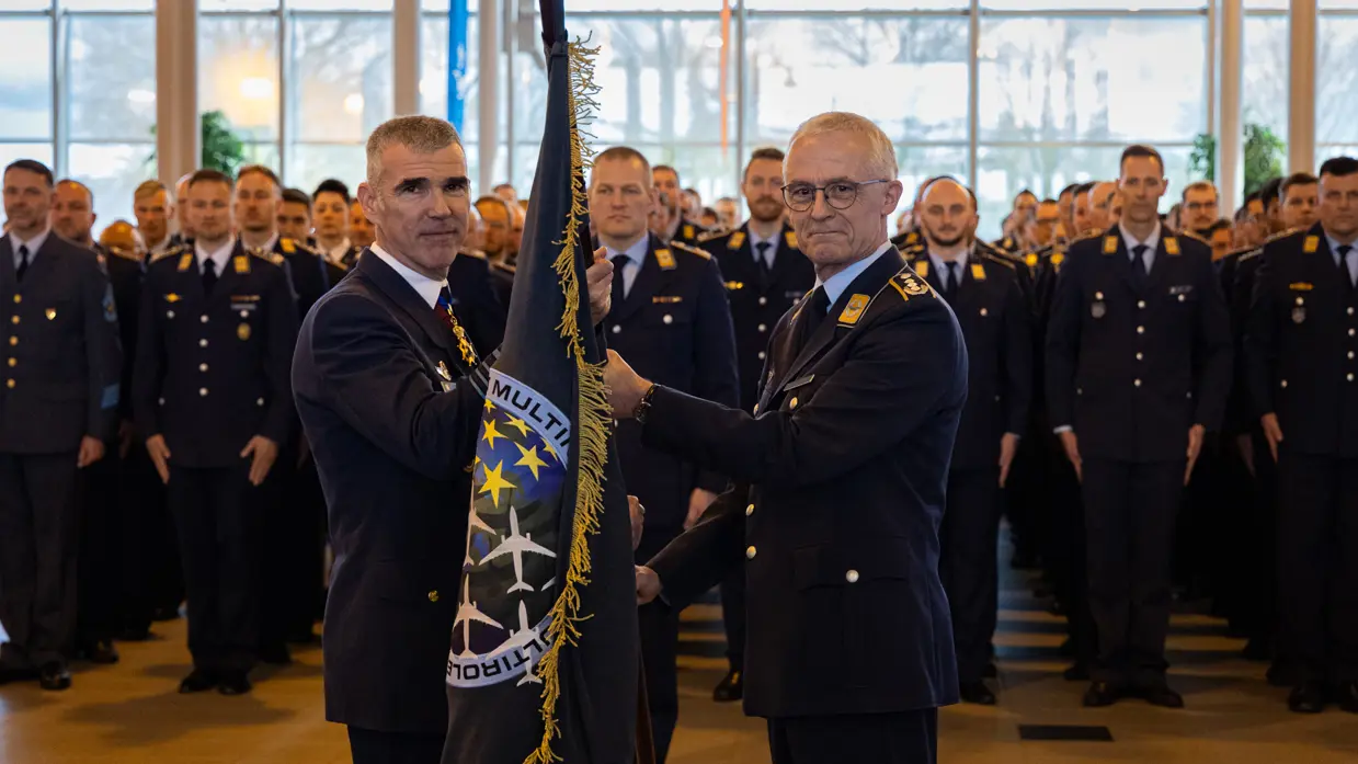 De scheidende (rechts) en aantredende commandant MMU die samen de onderdeelsvlag vasthouden.