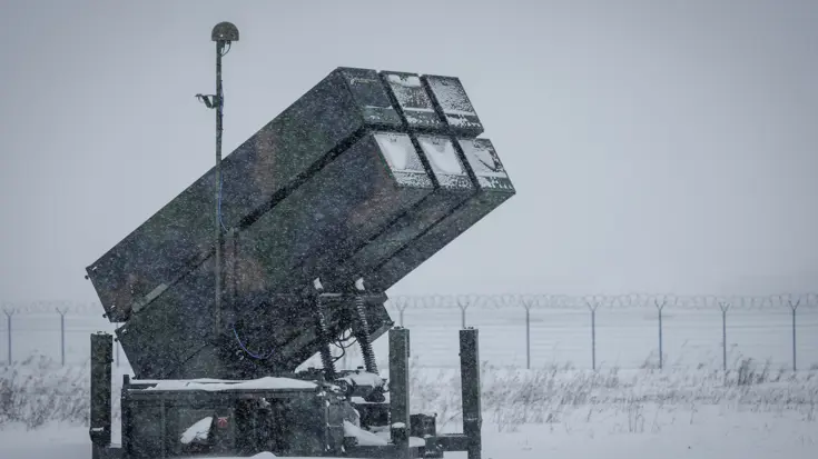 Links een counterdrone-apparaat met grote lenzen. Rechts een NASAMS-lanceerinstallatie in de sneeuw.