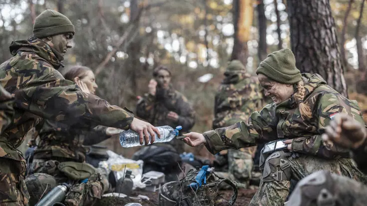 De deelnemers lunchen. Eentje schenkt water in met een plastic fles.